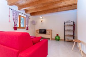 a living room with a red couch and a tv at Residence Rosental in Alleghe