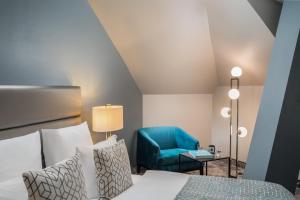 a bedroom with a bed and a blue chair at Hotel du Nord in Hamburg