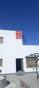un panneau rouge sur le côté d'un bâtiment blanc dans l'établissement الاردن جرش سوف المناره بالقرب من لواء قصبة جرش شاليه الكوت الاردني, à Khirbat Ra”s al Madīnah