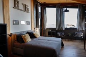 a bedroom with a bed and a couch and windows at Brouwersdam Stay in Ouddorp