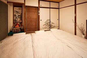 Cette chambre comprend un grand lit blanc et une fenêtre. dans l'établissement Walk to Nara Park-Nara's Timeless Stay, à Nara