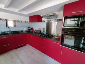 a kitchen with red cabinets and black counter tops at Gîte de Kairos in Savigné