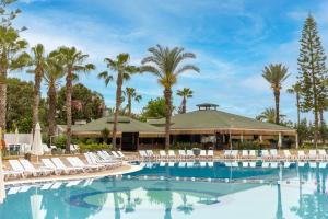 a large pool with chairs and palm trees at Holiday Park Resort - Ultra All İnclusive in Okurcalar