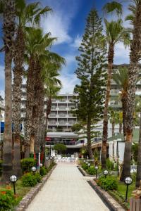 a walkway with palm trees in front of a building at Holiday Park Resort - Ultra All İnclusive in Okurcalar