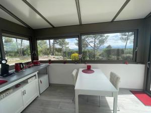 a kitchen with a white table and some windows at La Pinède du Lac in Esparron-de-Verdon