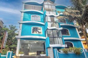 a blue building with palm trees in front of it at Ocean Wave - Calangute in Calangute