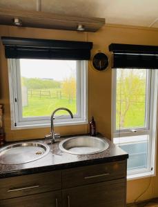 two sinks in a kitchen with two windows at Thorne Lodge - Seaview - 3 Bedroom in Whitstable
