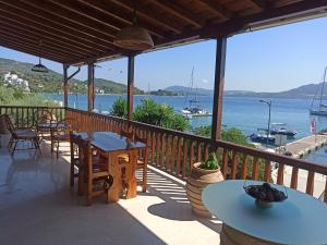 a porch with tables and chairs and a view of the water at Seaside Selana Home in Nikiana