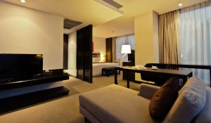 a living room with a couch and a television and a bed at Sunee Grand Hotel and Convention Center in Ubon Ratchathani