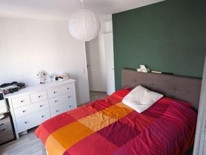 - une chambre avec un lit et une couverture colorée dans l'établissement Appartement terrasse sur le canal de l’ourcq, à Bobigny