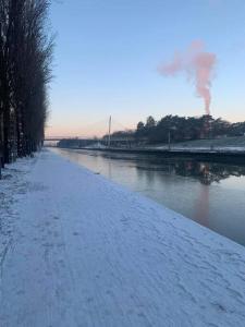 un chemin enneigé à côté d'une rivière avec un pont dans l'établissement Appartement terrasse sur le canal de l’ourcq, à Bobigny