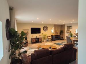 a living room with a couch and a table at La villa Terre & Mer avec piscine chauffée, proche de Cabourg in Escoville