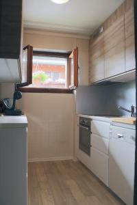 uma cozinha com armários brancos e uma janela em Les Sérandes em Lens