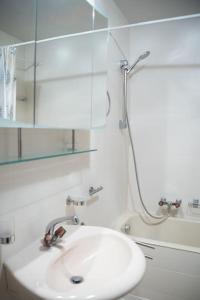 uma casa de banho branca com um lavatório e um chuveiro em Les Sérandes em Lens