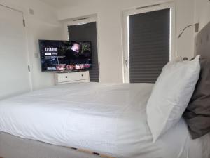 Elmers EndにあるBeckenham- PRIVATE DOUBLE Bedroom With En-suite in SHARED APARTMENTのベッドルーム(白い大型ベッド1台、薄型テレビ付)