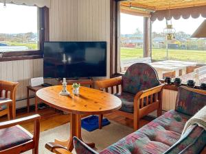 ein Wohnzimmer mit einem Tisch und einem TV in der Unterkunft Holiday home LAHOLM XIII in Laholm
