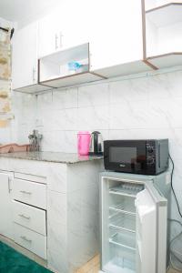 a kitchen with white cabinets and a microwave at House of L in Eldoret