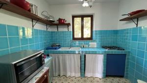 uma cozinha em azulejos azuis com um lavatório e um fogão em Villa Matteo San Teodoro em San Teodoro