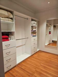 a walk in closet with white cabinets and a mirror at Private guest suite in Perth