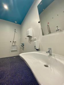 bagno con lavandino bianco e specchio di We Street Hostel - El Arenal-Albergue juvenil a El Arenal