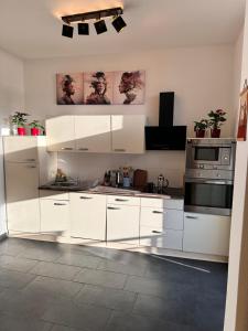 une cuisine avec des armoires blanches et une cuisinière dans l'établissement City Altstadt Appartement in unmittelbarer Nähe zu Saale und Marktplatz mit privatem Parkplatz, à Halle-sur-Saale
