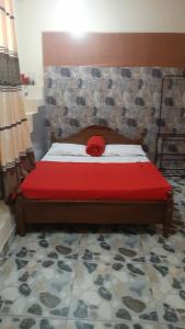 Una cama con una almohada roja encima. en Barrow Villa en Nuwara Eliya