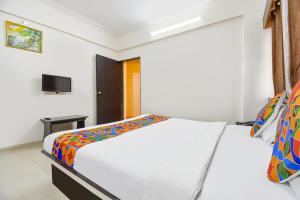 1 dormitorio con 1 cama y TV en la pared en FabHotel Yashraj Inn, en Vagholi