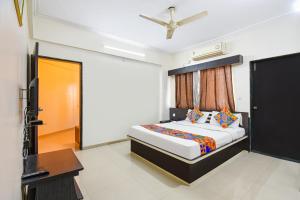 a bedroom with a bed and a desk and a television at FabHotel Yashraj Inn in Vagholi