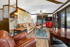 uma sala de estar com mobiliário de couro e uma televisão em Clutter Falls Retreat- Main House em New Braunfels