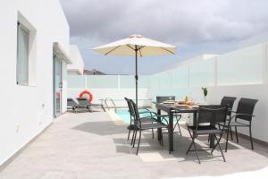 un patio avec une table, des chaises et un parasol dans l'établissement Villa Marina Rubicón DeLuxe, à Playa Blanca 35 autres photos