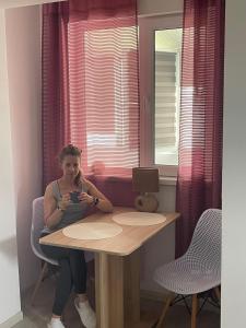 una mujer sentada en una mesa frente a una ventana en Ferienappartment Casasim, en Techirghiol