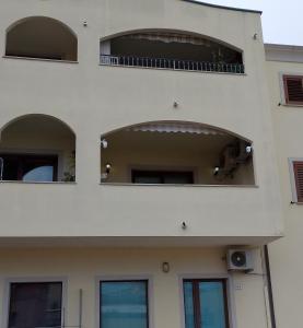 a white building with three windows and a balcony at Casa Vacanze Chiara in Olbia