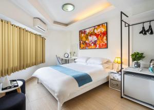 een slaapkamer met een groot wit bed en een schilderij aan de muur bij ELIOT HOTELs in Ho Chi Minh-stad