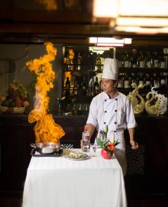 un chef de pie junto a una mesa con un plato de comida en Swan Cruises Halong, en Ha Long