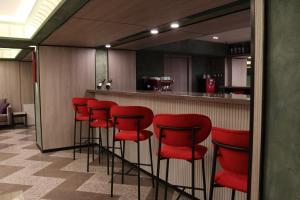 a bar with red bar stools in a room at Hotel Kazzhol Almaty in Almaty