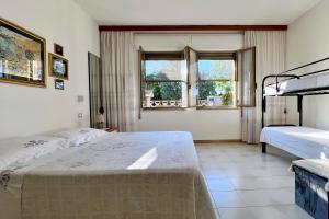 a bedroom with two beds and two windows at Gocciadoro guest apartment in Solanas