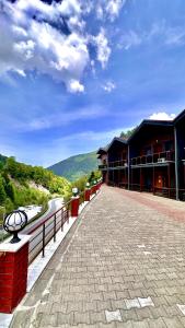 a large building with a walkway next to a river at Green Cinar Apart in Uzungol