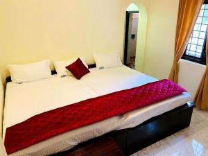 a bed with a red blanket on top of it at BOB Leisure in Ooty