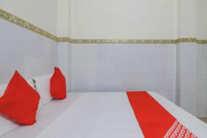 1 dormitorio con almohadas rojas y 1 cama blanca en OYO 79037 Metro Lodge en Hyderabad