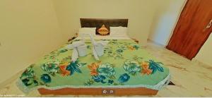 Una cama con una manta verde con una cruz. en Hotel Comfort Regency, en Bharatpur