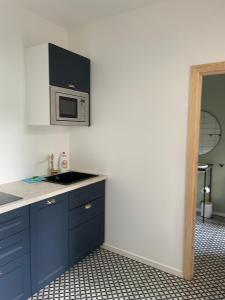 a kitchen with blue cabinets and a microwave at Sisters Beach Apartments in Liepāja