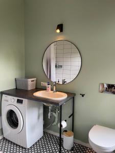 een badkamer met een wastafel en een wasmachine bij Sisters Beach Apartments in Liepāja
