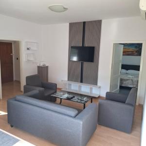 ein Wohnzimmer mit einem Sofa, 2 Stühlen und einem TV in der Unterkunft Barka Zadar in Zadar