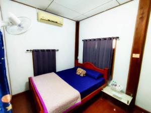 um pequeno quarto com uma cama azul e cortinas em BaanNakanoHomestay em Mae Rim
