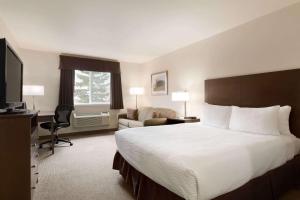 a hotel room with a large bed and a desk at Days Inn by Wyndham Steinbach in Steinbach