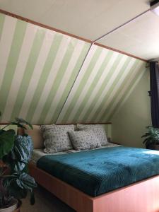 Bett in einem Zimmer mit gestreifter Decke in der Unterkunft Váradi Vendégház in Doboz