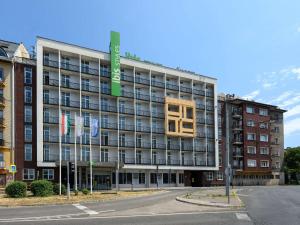 - un grand bâtiment avec un panneau vert dans l'établissement Ibis Styles Budapest City, à Budapest