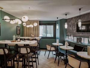 巴黎的住宿－巴黎埃菲爾鐵塔米拉波橋美居酒店，一间设有白色桌椅的餐厅,拥有绿色的墙壁