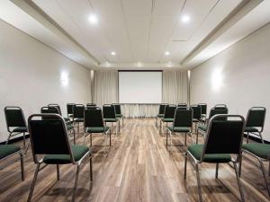 a conference room with chairs and a projector screen at ibis Betim in Betim