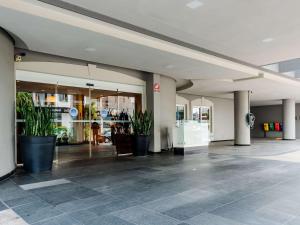 an empty lobby with potted plants in a building at ibis Joinville in Joinville
